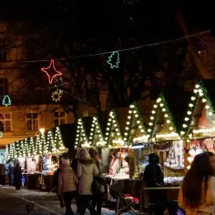 Magiczny jarmark bożonarodzeniowy w Lublinie nocą. Kolorowe gwiazdy i choinki rozświetlają ulicę, a stragany kuszą świątecznymi ozdobami.