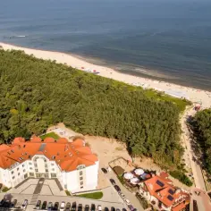 Widok z lotu ptaka na hotel, las i plażę nad Bałtykiem.