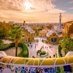 Park Güell w Barcelonie, jeden z najpiękniejszych miast Hiszpanii, zachwyca mozaikową ławką i bajkowymi budynkami o zachodzie słońca.