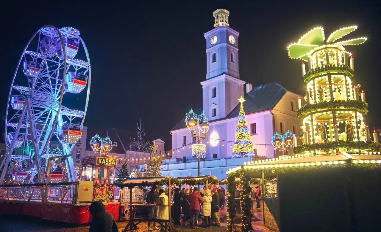 Gliwice jarmark bożonarodzeniowy nocą. Wesołe miasteczko, iluminacje, choinka i świąteczna piramida.