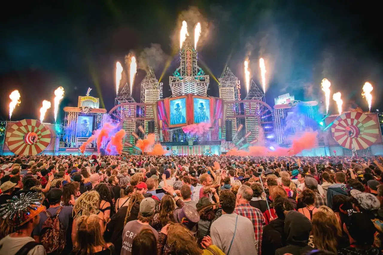 Tłum ludzi na jednym z największych festiwali muzycznych w Europie, z efektami pirotechnicznymi i widowiskową sceną.