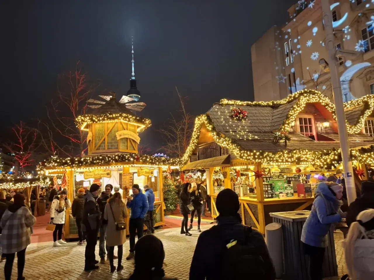 Jarmark świąteczny w Berlinie nocą, rozświetlony tysiącami lampek. W tle widać wieżę telewizyjną.