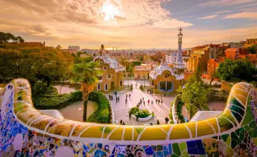Park Güell w Barcelonie, jeden z najpiękniejszych miast Hiszpanii, zachwyca mozaikową ławką i bajkowymi budynkami o zachodzie słońca.