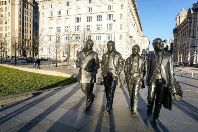 Pomnik Beatlesów na tle budynków w mieście beatlesów.